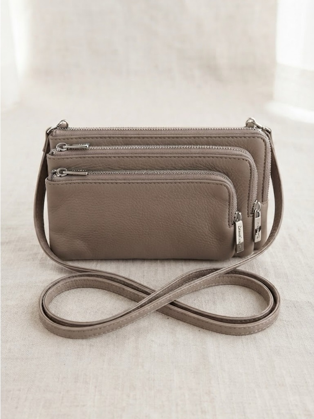 Brand new without tags 
Danier Taupe Triple-Zip Crossbody Bag